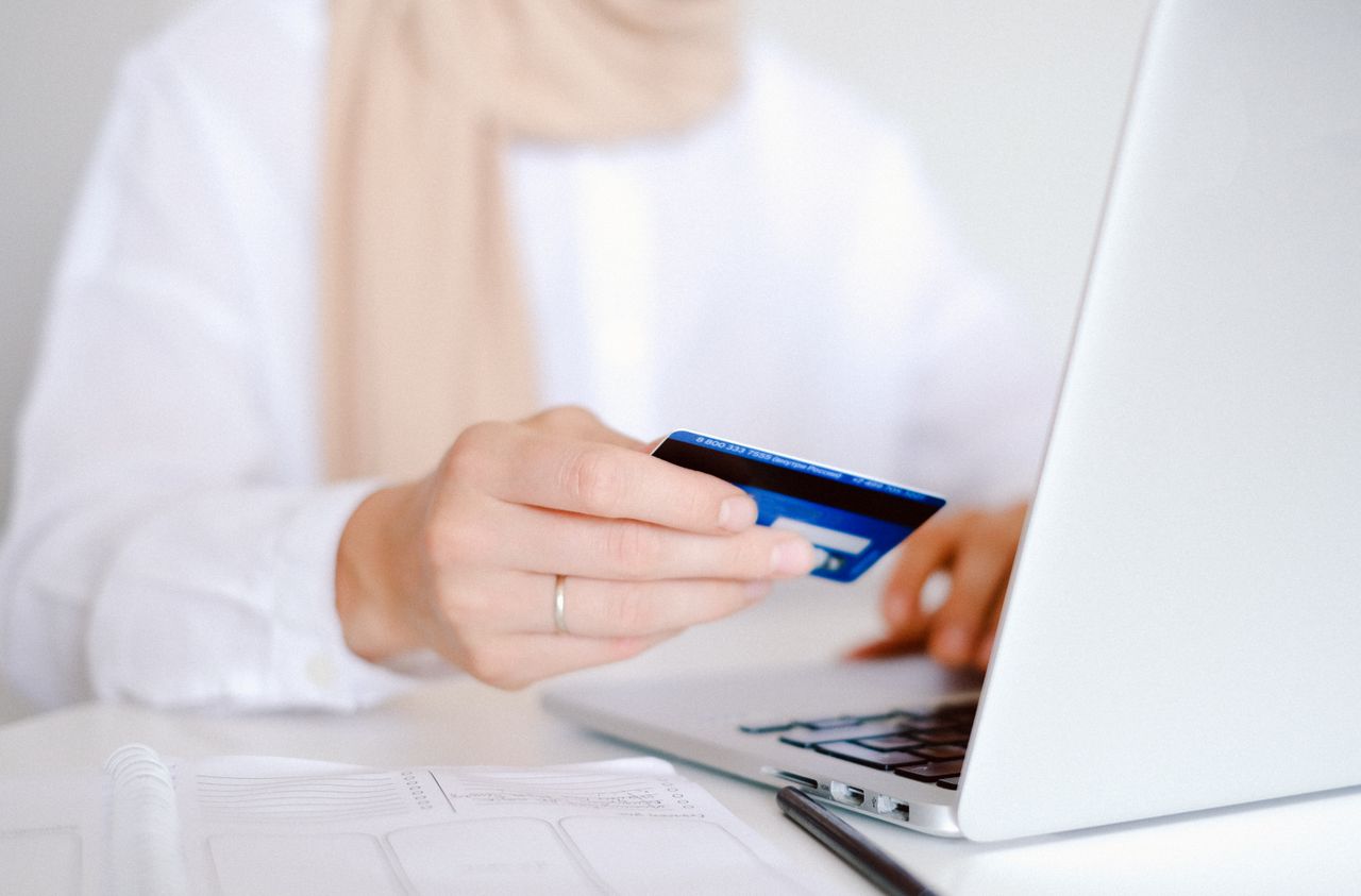 hero-img-01 Close-up of a person holding a credit card while using a laptop for online shopping.